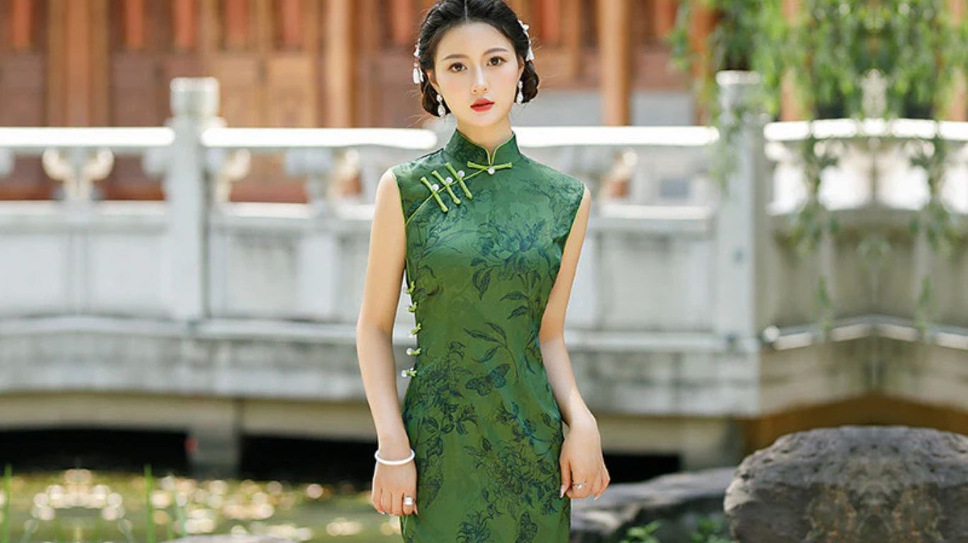 Modern woman wearing a qi pao with high collar, side slits, fitted silhouette, and floral embroidery in a sunlit garden, showcasing elegance and tradition.